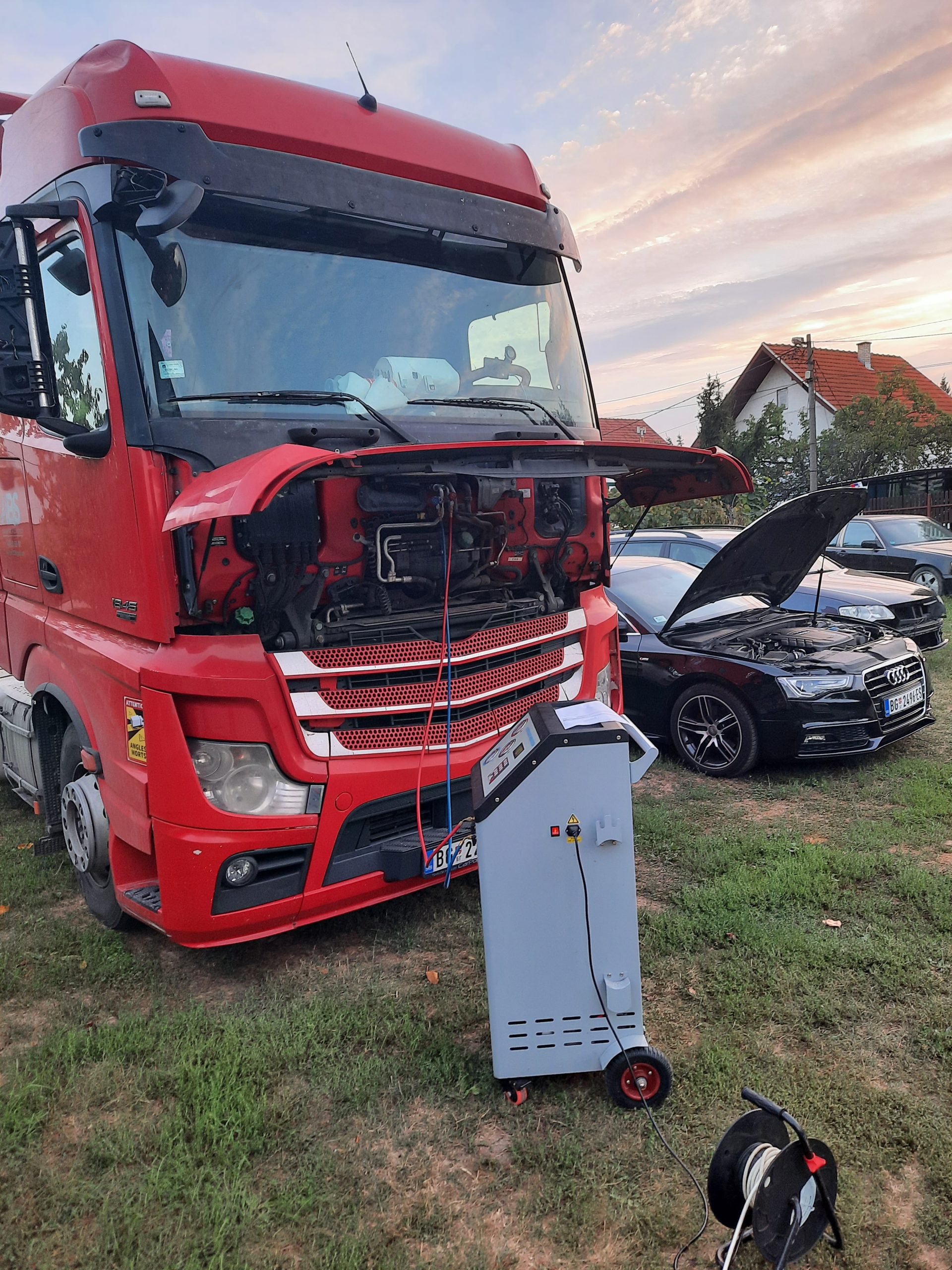 a red truck with the hood open next to a car